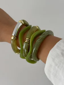 Detailopname van een set gelaagde groene hars armbanden met een bamboe ontwerp.