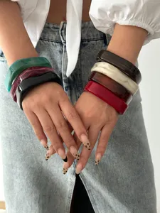 Close-up van stijlvolle onregelmatige acryl armbanden in diverse kleuren om de pols van model.