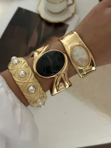 Vintage grobe Goldarmreifen mit Perlen und schwarzem Emaille Stein im Detail am Arm.