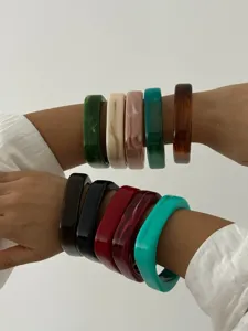 Gedetailleerde weergave van kleurrijke acryl armbanden met marmerpatronen op modelarmen