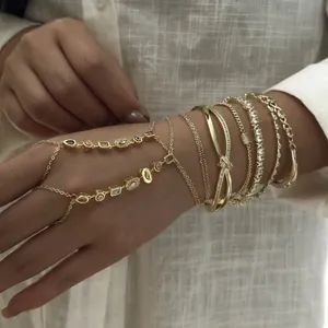 Primer plano de pulseras de cadena doradas apiladas y conjunto de cadena de mano