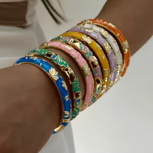 Close-up of vibrant enamel gilded floral bangles with rhinestone details on wrist