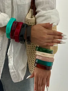 Gedetailleerde weergave van kleurrijke, dikke, gemarmerde acryl armbanden op een model.