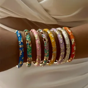 Close-up detail of colorful enamel gold floral bangles with hollow rhinestone design