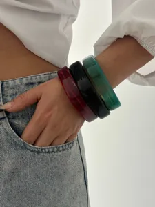 Dichtbij van drie kleurrijke minimalistische geometrische acryl armbanden om de pols