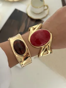 Nahaufnahme von Retro-Armreifen in Goldoptik mit roten und braunen Edelsteinen.