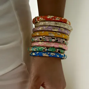 Detailed view of stacked vintage enamel floral bangles with gold-plated spring design.