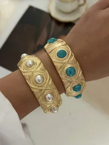 Detailansicht von breiten Vintage-Goldarmbändern mit Perlen und Türkis am Handgelenk