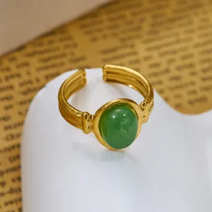 Dettaglio di un anello vintage dorato con una pietra di occhio di tigre verde lucida.