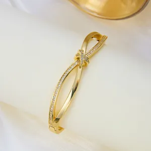 Detalle de una elegante pulsera rígida dorada con nudo y circonitas brillantes