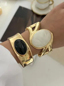 Detailansicht von Vintage Goldarmreifen mit schwarzen und weißen Edelsteinen auf Haut.