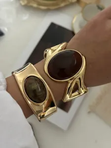 Detail von goldenen Vintage-Armreifen mit großen bernsteinfarbenen und grünen Edelsteinen