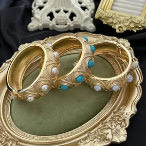 Detaillierte Nahaufnahme goldener Vintage-Armreifen mit Türkis- und Perleneinlagen