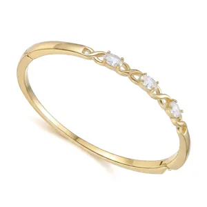 Detalle elegante de un brazalete dorado con tres piedras blancas óvalas brillantes