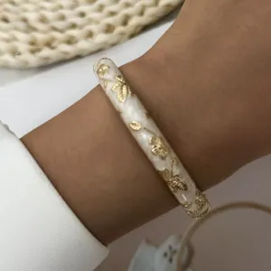 Close-up detail of a vintage Chinese style white enamel bracelet with gold floral pattern