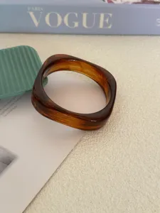 Detail van een bruin gemarmerde acryl armband met een onregelmatig geometrisch design.
