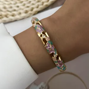 Close-up of retro Chinese style gold-plated floral bangle with hollowed enamel detail.