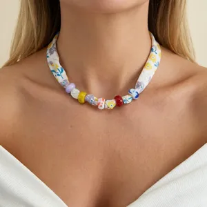 Primer plano detallado de un collar de tela con flores bohemias y cuentas de colores.