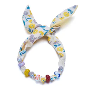 Primer plano de collar de tela floral con cuentas de colores y lazo