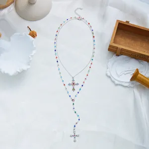 Détail d'un collier en Y à double rangée avec des strass colorés et des pendentifs en croix.