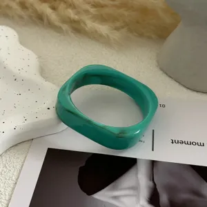 Close-up van een groene gemarmerde acryl armband met een onregelmatig geometrisch ontwerp
