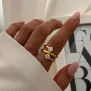 Detaillierte Makroansicht eines goldenen Wickelrings mit zwei runden klaren Steinen.