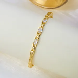 Elegante brazalete dorado con cristales transparentes ovalados y diseño de nudo.