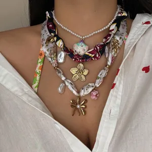 Vista detallada de un collar bohemio con perlas, pañuelos de seda y colgantes de oro