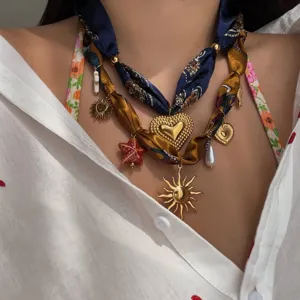Dettaglio di una collana in nastro di seta boho con ciondoli sole, cuore e stella