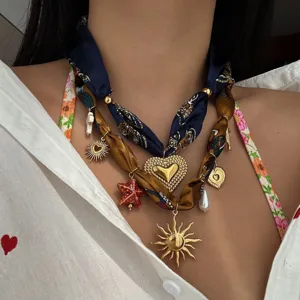 Vista dettagliata di una collana in nastro di seta a più strati con ciondoli sole e cuore.