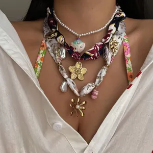 Detalle del collar tipo bufanda de acero inoxidable con perlas y dijes florales