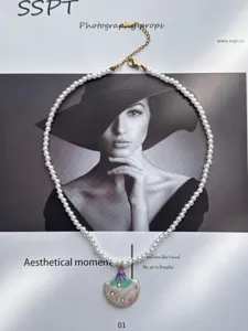 Detalle artístico de collar de perlas con colgante de caracola colorida sobre un fondo