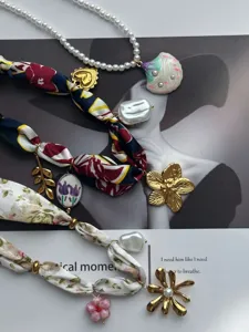 Vista detallada de collares estilo bohemio con bufandas de seda, perlas blancas y dijes