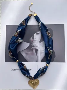 Dettaglio di una collana in nastro di seta blu navy con pendente a cuore in oro testurizzato