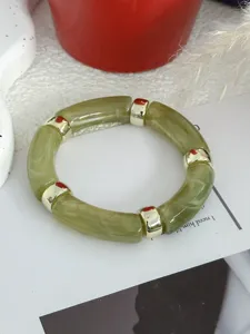 Detailopname van een groene bamboe hars armband met goudkleurige metalen tussenstukken