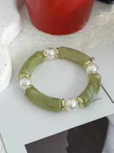 Detailweergave van retro bamboe-stijl armband met groene segmenten en witte parels