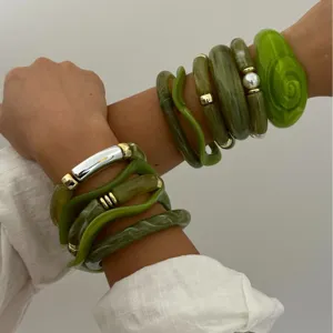 Gestapelde groene acryl armbandenset met bamboe-stijl hars en gouden metaalaccenten.
