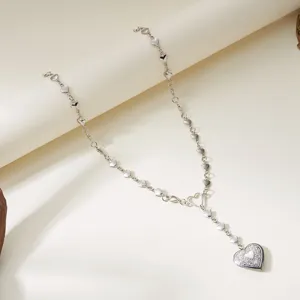 Detail view of silver heart link necklace with vintage engraved locket pendant