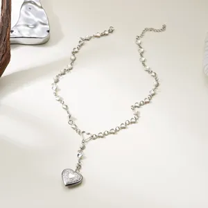Close-up of a silver heart locket necklace with delicate heart-shaped chain links