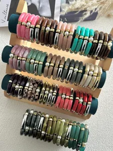 Dettaglio di braccialetti in acrilico colorato con perle su un espositore in legno