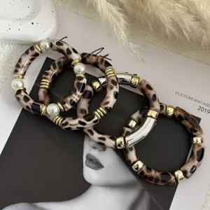 Dettaglio dei braccialetti retrò in acrilico maculato con perle e accenti dorati.
