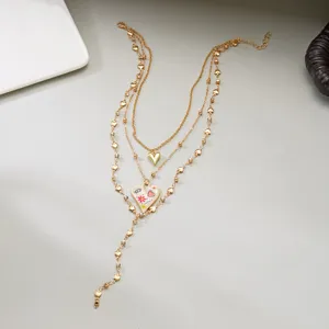 Detailed view of multi-layered gold chain necklace with enamel heart pendant and rhinestones