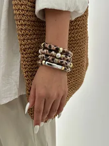 Vista dettagliata del set di braccialetti in acrilico con stampa leopardata al polso.