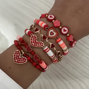 Detail view of stacked Valentine's Day bracelets with red heart charms and beads.