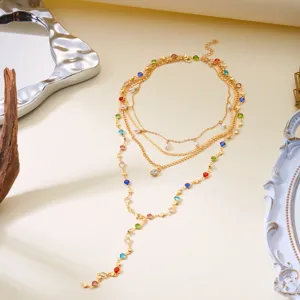 Close-up of a multi-layered gold necklace featuring colorful rhinestones and pearls