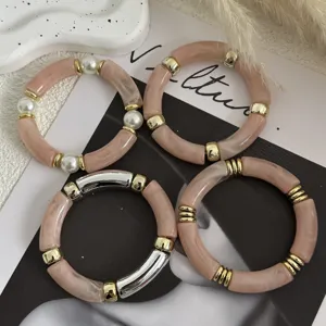 Primo piano di bracciali in acrilico stile Maillard con perle e dettagli dorati.