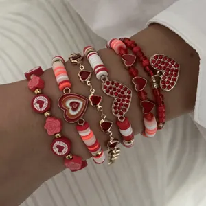 Close-up of Valentine's Day red heart stacked bracelet set with beads and gold pendants.