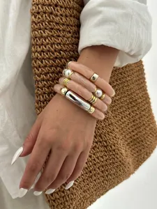 Dettaglio del bracciale in acrilico rosa con perle e accenti in metallo dorato
