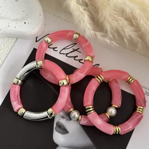 Dettaglio di bracciali retrò in acrilico rosa con accenti dorati e trama marmorizzata