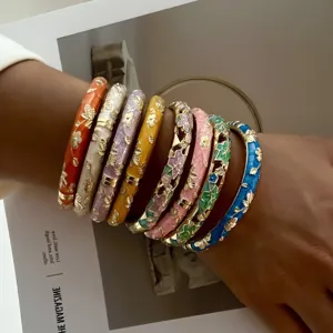Stack of ethnic style enamel bangles with gilded flower patterns on wrist